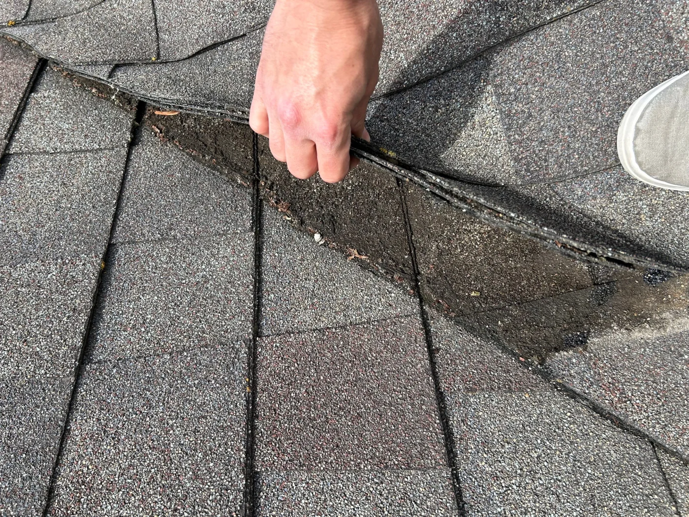 Detailed Roof Inspection Kaukauna Wi Wisconsin Exteriors A close-up of a roofer’s hand lifting up shingles on a roof during an inspection.