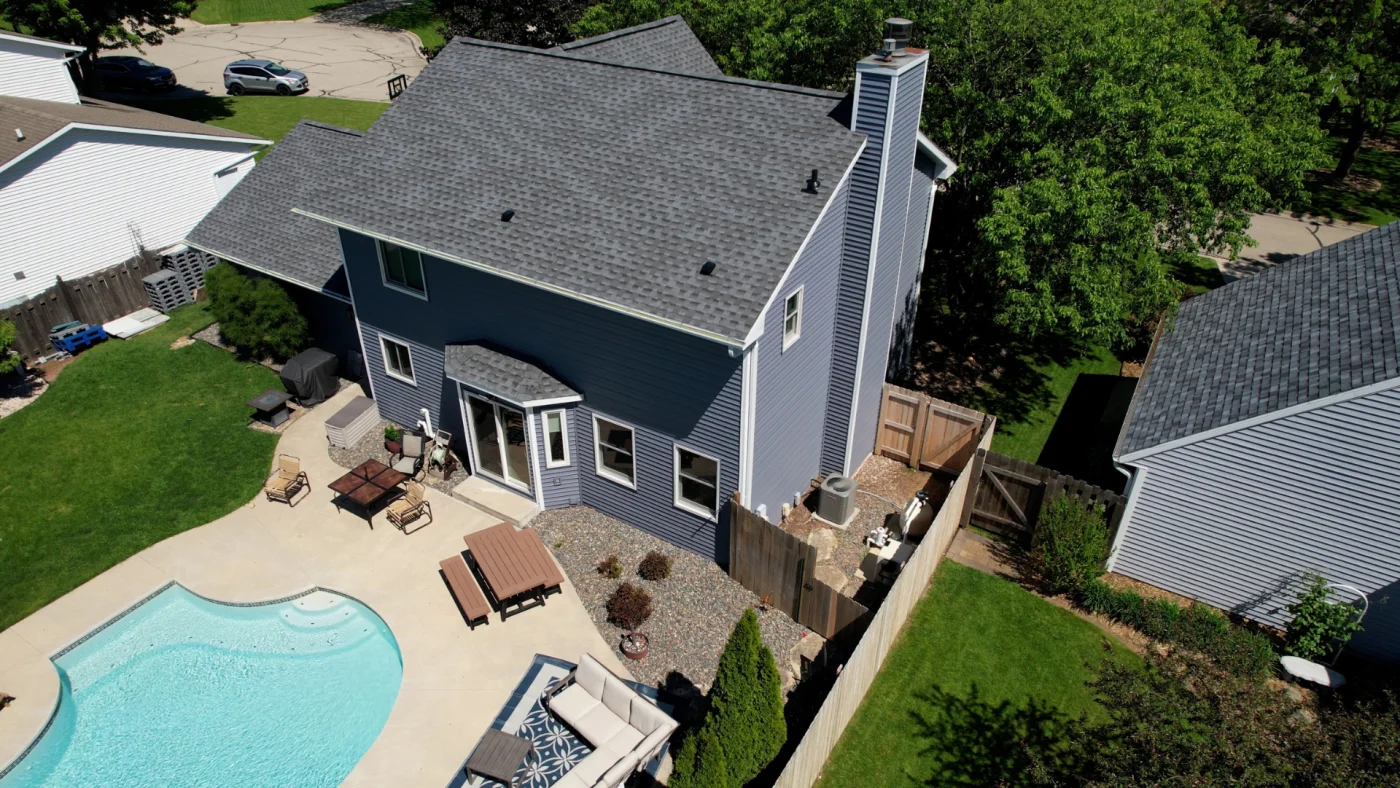 Excellent Roofing Appleton Wi Wisconsin Exteriors An aerial view of the back of a two-story blue house with an asphalt shingle roof and white windows