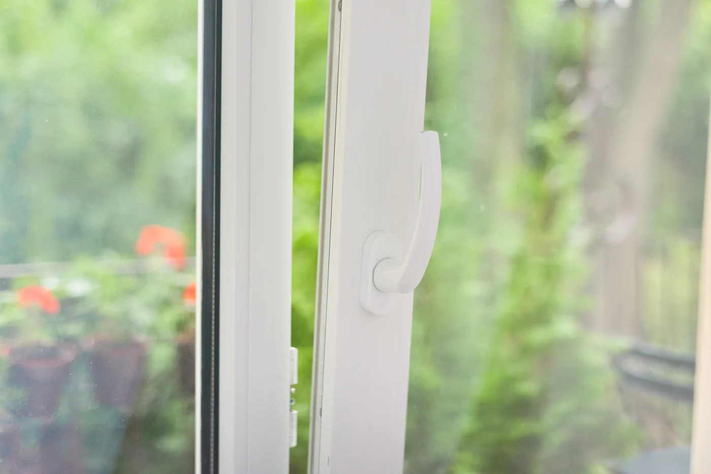 A close-up view of a slightly open white vinyl window from the inside.